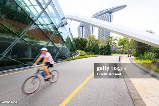 a bicycle riding along botanic garden in a modern city with marina bay sands in background - loisir ストックフォトと画像