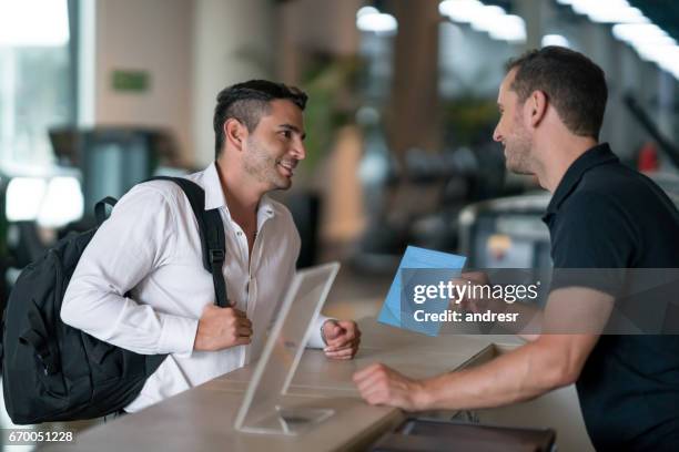 man at the gym talking to receptionist about membership plans - gym receptionist stock pictures, royalty-free photos & images