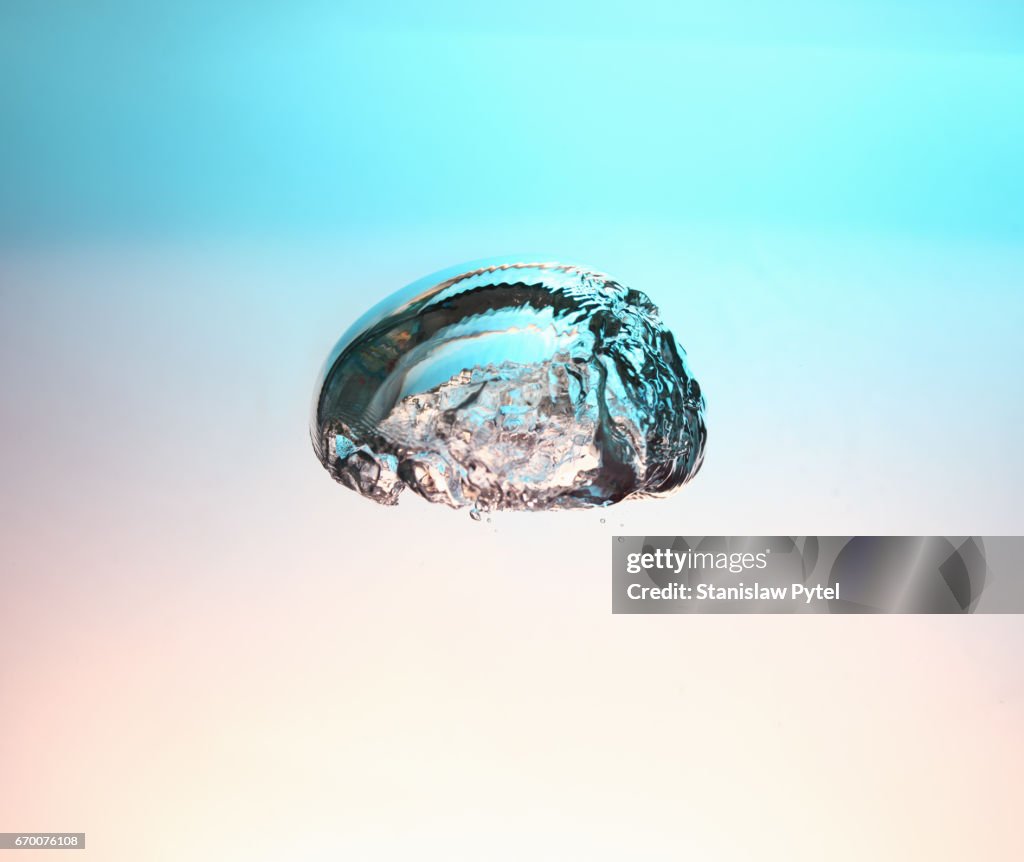 Air bubble rising in water against background of pastel colors