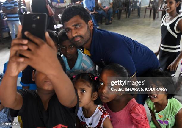 Sri Lankan cricketer Rangana Herath meets with young survivors and displaced people at a relief camp after a massive garbage mountain collapse in the...