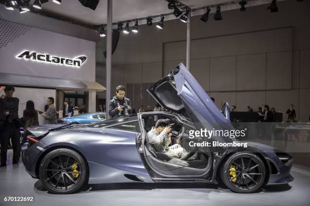 An attendee takes a photograph inside a McLaren Automotive Ltd. 720S luxury automobile at the Auto Shanghai 2017 vehicle show in Shanghai, China, on...