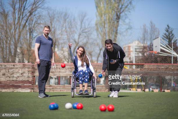 young woman in a wheelchair and his friends are playing boccia - bocce ball stock pictures, royalty-free photos & images