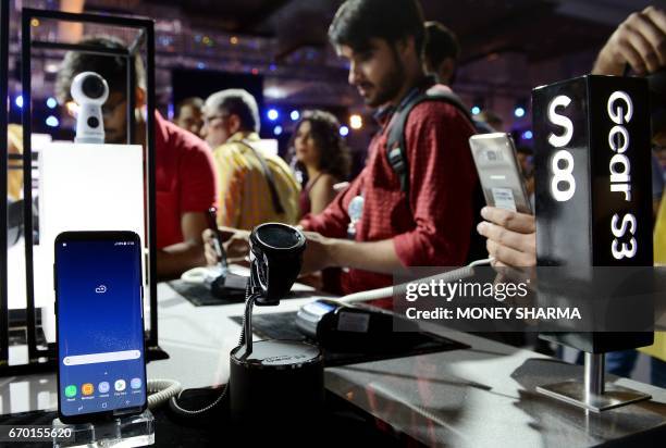 People look at the newly launched Samsung Galaxy S8 and Galaxy S8+ smartphones during an event in New Delhi on April 19, 2017. / AFP PHOTO / MONEY...