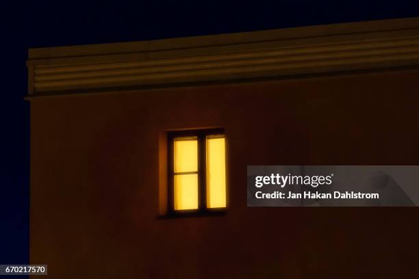 lit window in apartement house - creepy house at night stock-fotos und bilder