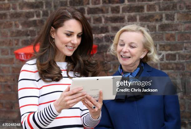 Catherine, Duchess of Cambridge speaks with Royal Mail CEO Moya Greene after they put a Heads Together headband onto the Kensington Palace post-box...