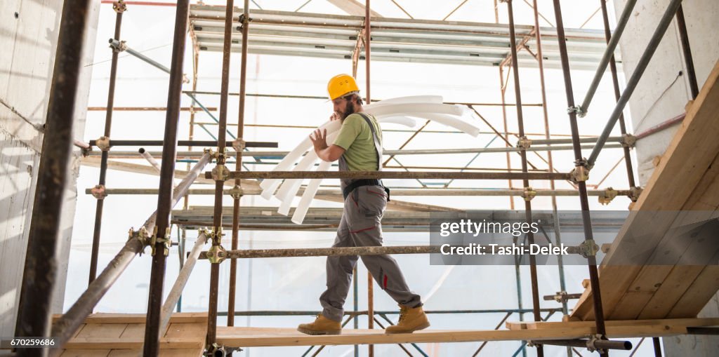 Worker Carrying Pipes