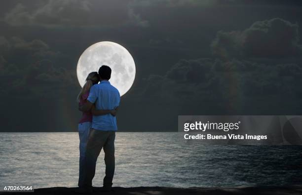 couple watching full moon over the ocean - supermoon stock-fotos und bilder