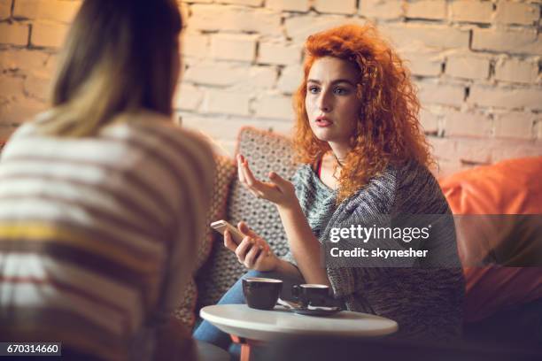 young redhead woman discussing with a friend in cafe. - friends serious stock pictures, royalty-free photos & images