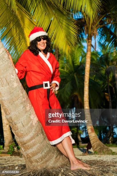 前視圖的聖誕老人女人有長頭髮和太陽的眼鏡，倚在加勒比看到納蘭霍奇科海灘島上的棕櫚樹的畫像 - caribbean christmas 個照片及圖片檔
