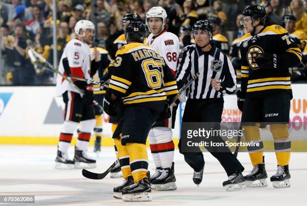 Boston Bruins left wing Brad Marchand and Ottawa Senators left wing Mike Hoffman jaw as linesman Brad Kovachik moves in during Game 3 of a first...