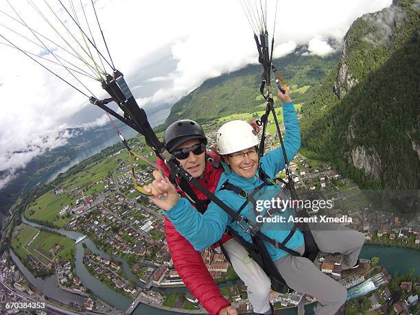 tandem parasailers descend over city and mountains - parapente fotografías e imágenes de stock