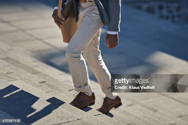 businessman walking on staircase with shoulder bag - hinauf bewegen stock-fotos und bilder