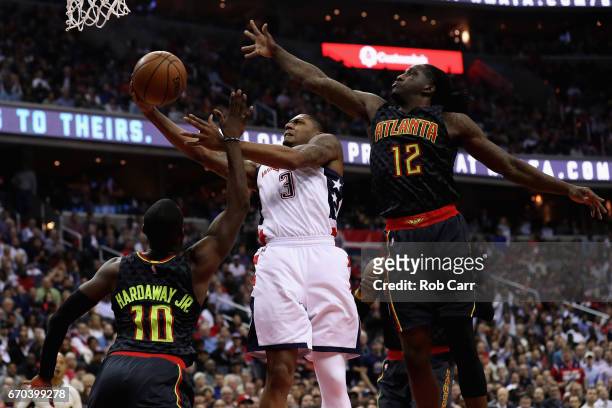 Bradley Beal of the Washington Wizards puts up a shot between Tim Hardaway Jr. #10 and Taurean Prince of the Atlanta Hawks in the first half of Game...