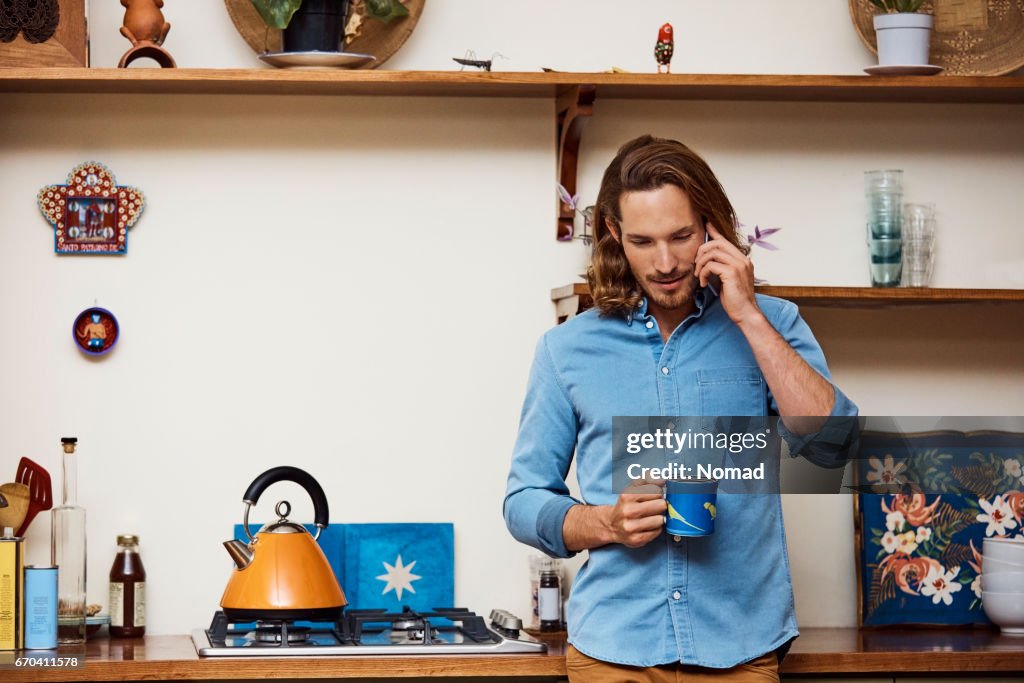 Homme à l’aide de téléphone portable tout en tenant la tasse à café