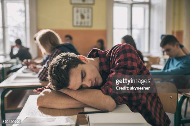 vermoeide student een dutje doen tijdens een lezing in de klas. - sleeping boys stockfoto's en -beelden
