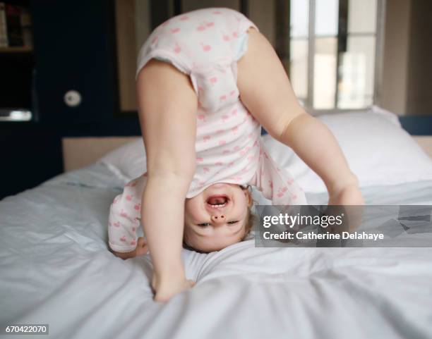 a baby girl playing on a bed - funny baby girl clothes photos et images de collection