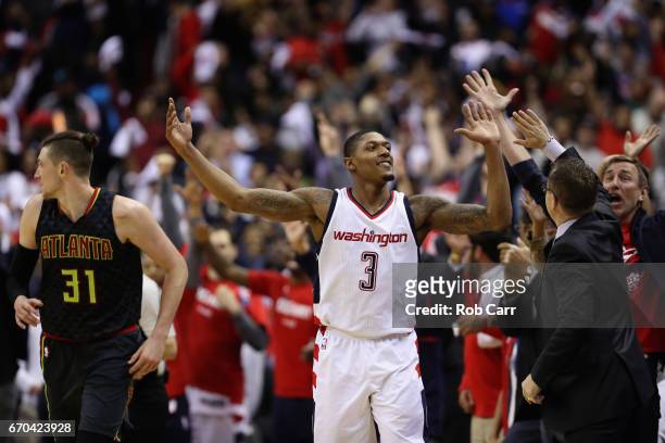 Bradley Beal of the Washington Wizards celebrates with head coach Scott Brooks in front of Mike Muscala of the Atlanta Hawks after hitting a three...