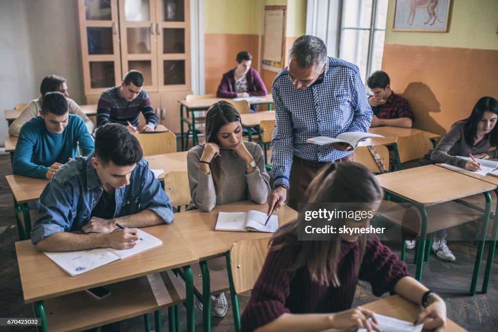 Teacher assisting a female student with studying in the classroom.