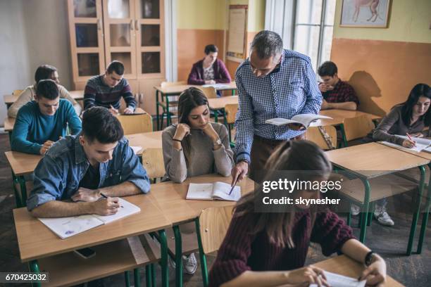 teacher assisting a female student with studying in the classroom. - high school building stock pictures, royalty-free photos & images