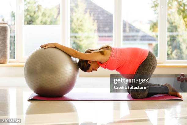 mid adult pregnant woman is exercising with a ball - fitness ball stock pictures, royalty-free photos & images