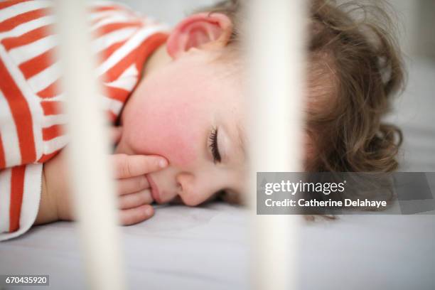 a 2 years old boy sleeping in his bed - 指をくわえる ストックフォトと画像