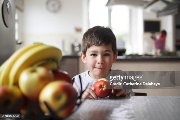 a boy eating an apple in the kitchen - aliments et boissons ストックフォトと画像