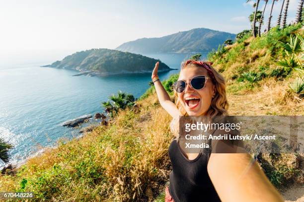 young woman takes selfie, on hillside above sea - asian happy adventure stock pictures, royalty-free photos & images