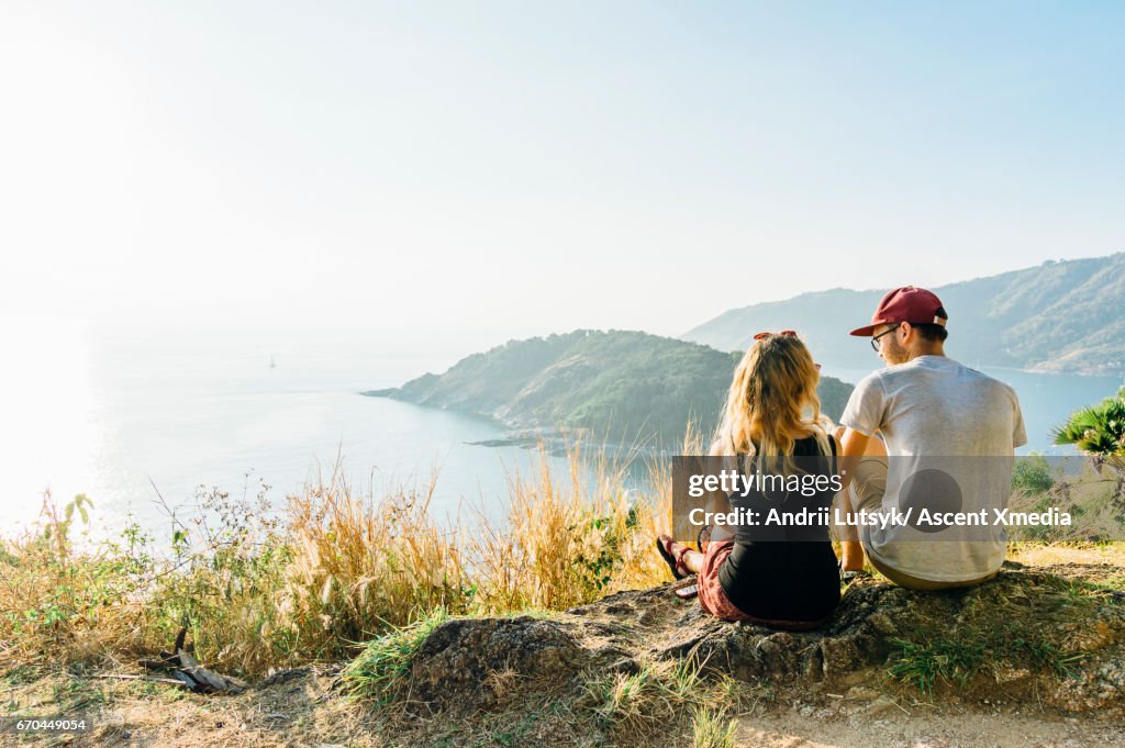 Young couple relax, on hillside above sea