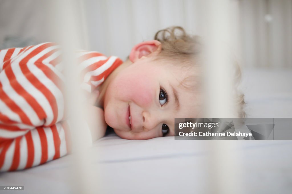A 2 years old boy waking up from his nap in his bed