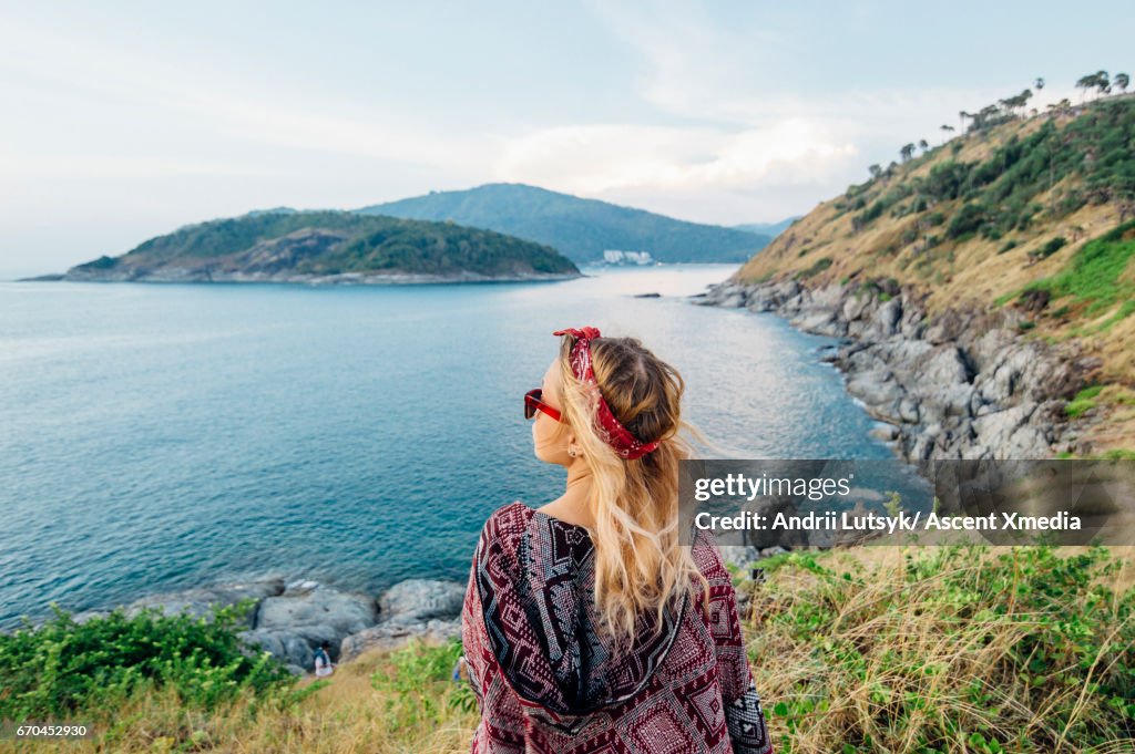 Young woman relaxes, on hillside above sea