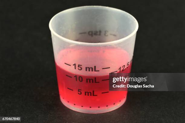 liquid cough syrup in a small measuring cup - measuring cup imagens e fotografias de stock