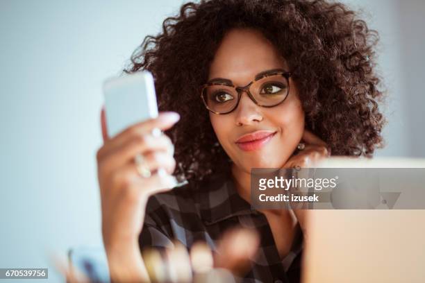 gelukkig jonge vrouw met een bril met behulp van slimme telefoon - happy face glasses stockfoto's en -beelden