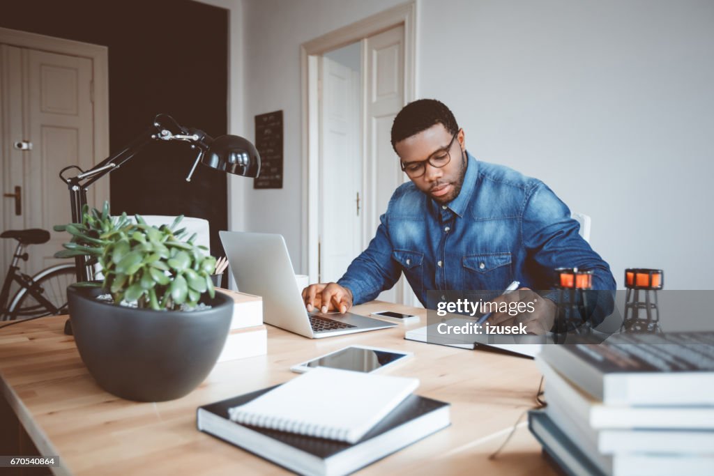Afro Amerikaanse jonge man aan het werk thuis kantoor