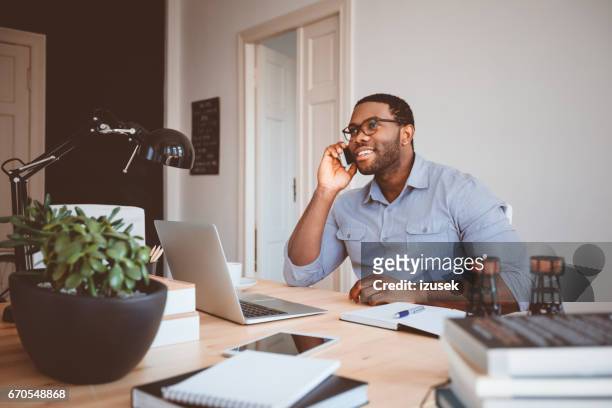 jonge zakenman op kantoor aan huis praten over telefoon - executive editor stockfoto's en -beelden