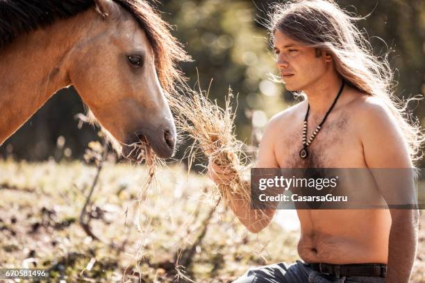 shirtless jonge man voeding paard - tough love stockfoto's en -beelden