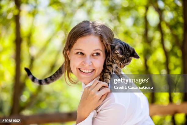 beautiful young woman enjoying with her cat on shoulders - cat and owner stock pictures, royalty-free photos & images