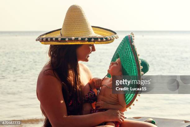 lächelnde mutter und ihr baby am strand - eltern baby stockfoto's en -beelden