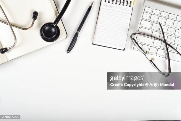 white table top view with medical essentials stethoscope, notepad, pen, computer keyboard, eyeglasses - desk aerial view stock pictures, royalty-free photos & images