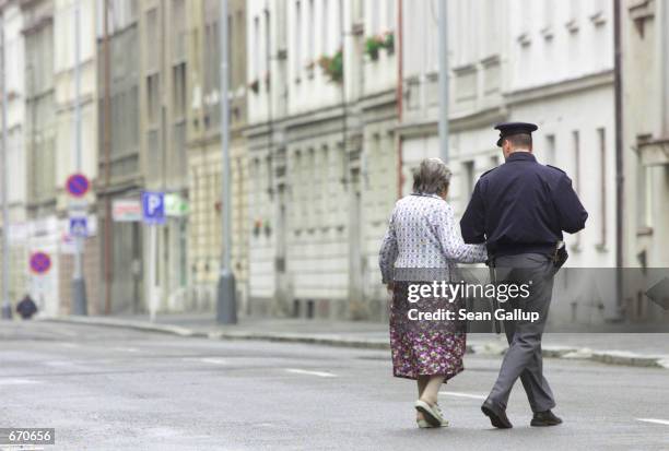 Czech city policeman escorts an old woman September 21, 2000 to her home on a closed street near the Prague Congress Center where International...