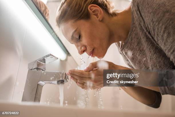 below view of a woman washing her face in the bathroom. - lavar imagens e fotografias de stock