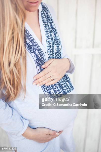 donna incinta. mani sul pancione. camicia a righe con ricamo. - crescita stock-fotos und bilder