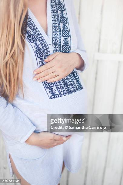 donna incinta. mani sul pancione. camicia a righe con ricamo. - capelli lisci fotografías e imágenes de stock