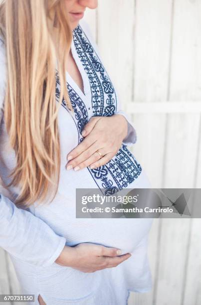 donna incinta. mani sul pancione. camicia a righe con ricamo. - capelli lisci fotografías e imágenes de stock