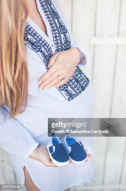 donna incinta. mano sul pancione. camicia a righe con ricamo. scarpine blu in mano. - capelli lunghi 個照片及圖片檔