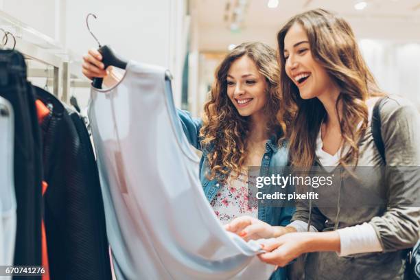 2 人の陽気な女の子の服のための買い物 - 小売 ストックフォトと画像