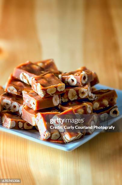 caramelled nougat candy with hazel nuts served on the rectangular plate - nougat stock pictures, royalty-free photos & images