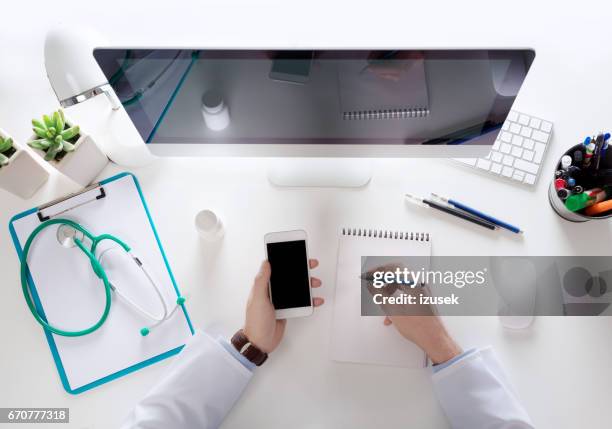 top view of doctor sitting at the desk and using smart phone - doctor desk stock pictures, royalty-free photos & images