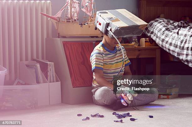 boy wearing home made virtual reality headset - child's bedroom stockfoto's en -beelden