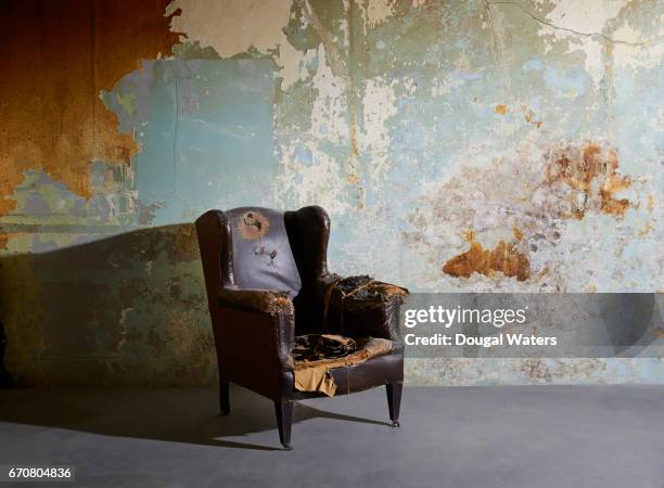 old vintage arm chair in decaying room with paint peeling from wall. - marcio foto e immagini stock