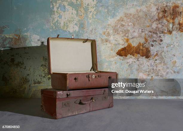 vintage suitcases in room with decaying wall. - vintage luggage stock pictures, royalty-free photos & images